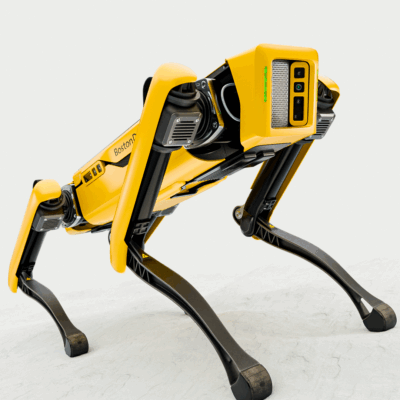 A yellow, dog-like quadruped robot with black legs stands on a light surface, facing slightly to the right. The robot has cameras and sensors on its front and is labeled "Boston Dynamics.