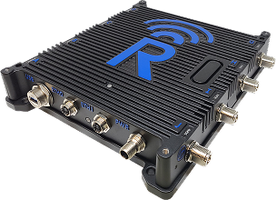A rugged black electronic device with a blue "R" logo, ribbed surface, and multiple labeled metal ports for connections on its sides, likely a communication or networking module.