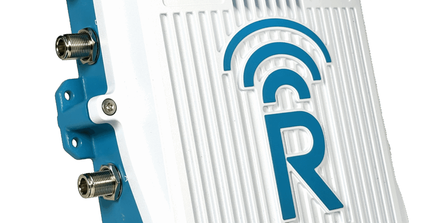 A white and blue electronic device with multiple ports and a large letter "R" on the front, along with a wireless signal icon and the text "Powered by Rajant Health.