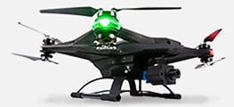 A black quadcopter drone with a mounted camera, glowing green light on top, and red-tipped rotor, viewed from the side against a white background.