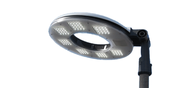 A modern, circular LED streetlight with a central open ring, mounted on a pole against a plain light background.