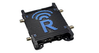 A black electronic device with four protruding connectors and a ribbed surface, featuring a large blue letter "R" and a wireless signal icon on top.