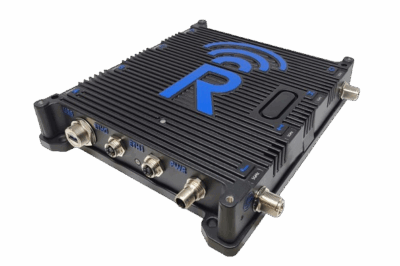 A black electronic device with ridged casing, multiple metal ports on one side, and a large blue letter "R" with a wireless signal icon on top. The device rests on a white background.