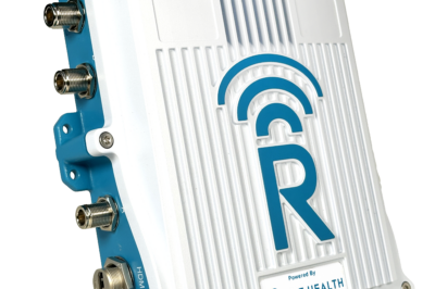 A white and blue electronic device with multiple ports on the side, large “R” logo, and labeled “Powered by Rajant Health” on the front panel. The design features ridged texture and wireless signal icon.