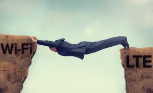 A man in a suit stretches across a gap between two cliffs labeled "Wi-Fi" and "LTE," symbolizing bridging the connection between wireless and cellular networks.