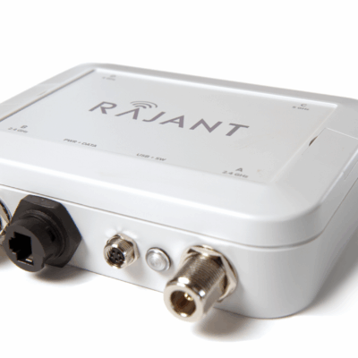 A white Rajant electronic device with labeled ports including Ethernet, power, and coaxial connectors, shown on a plain white background.