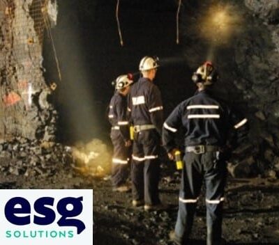 Three workers in safety gear and helmets stand inside a rocky underground mine, facing a dark tunnel. The ESG Solutions logo appears in the bottom left corner.