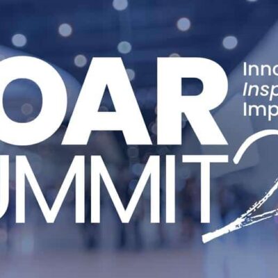 White text reading "SOAR SUMMIT 24" and "Innovate. Inspire. Impact." is overlaid on a blurred background of people walking inside a modern building.