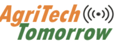 Logo with the words "AgriTech Tomorrow" in orange and green text. The word "AgriTech" is orange, and "Tomorrow" is green. There is a wireless signal icon next to "Tech".