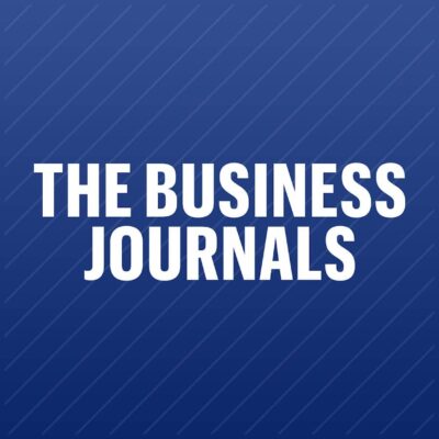 White bold text reading "THE BUSINESS JOURNALS" is centered on a blue background with diagonal lines.
