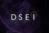 The letters "DSEI" appear in bold white font on a dark background with faint geometric patterns and a circular target symbol around the letter "I.