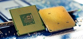Two computer processor chips with rows of gold pins on the bottom are placed side by side on a blue circuit board, showing their intricate details and electronic connections.