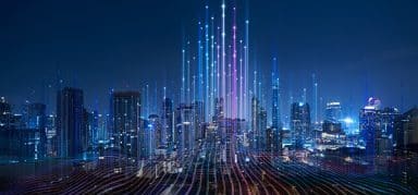 A futuristic city skyline at night with glowing data lines and digital light beams rising from the buildings, symbolizing advanced technology and connectivity.