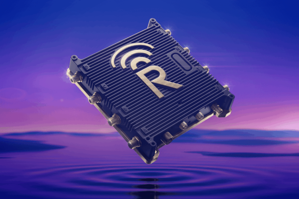 A black electronic device with a large "R" and a wireless signal icon on top floats above calm water, illuminated by a purple and blue sky.