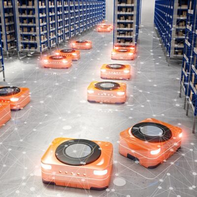 Orange autonomous robots move along the floor between tall shelves in a warehouse, carrying goods. Digital network graphics overlay the image, suggesting automation and smart logistics technology.