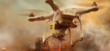 A white quadcopter drone with a camera flies over a cityscape at sunset, surrounded by clouds and warm light.