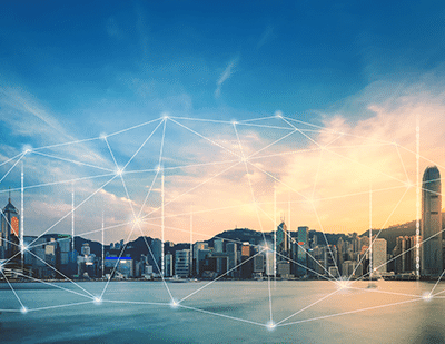 A city skyline at sunset with digital lines and nodes superimposed, representing a connected smart city across the waterfront.