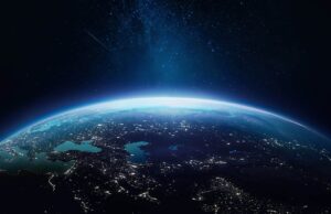 View of Earth from space showing a curved horizon, illuminated landmasses, bright city lights, and a star-filled night sky above.