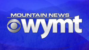 The WYMT Mountain News logo features bold white text with the CBS eye logo on a blue background with faint mountain silhouettes.