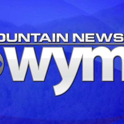 The WYMT Mountain News logo features bold white text with the CBS eye logo on a blue background with faint mountain silhouettes.